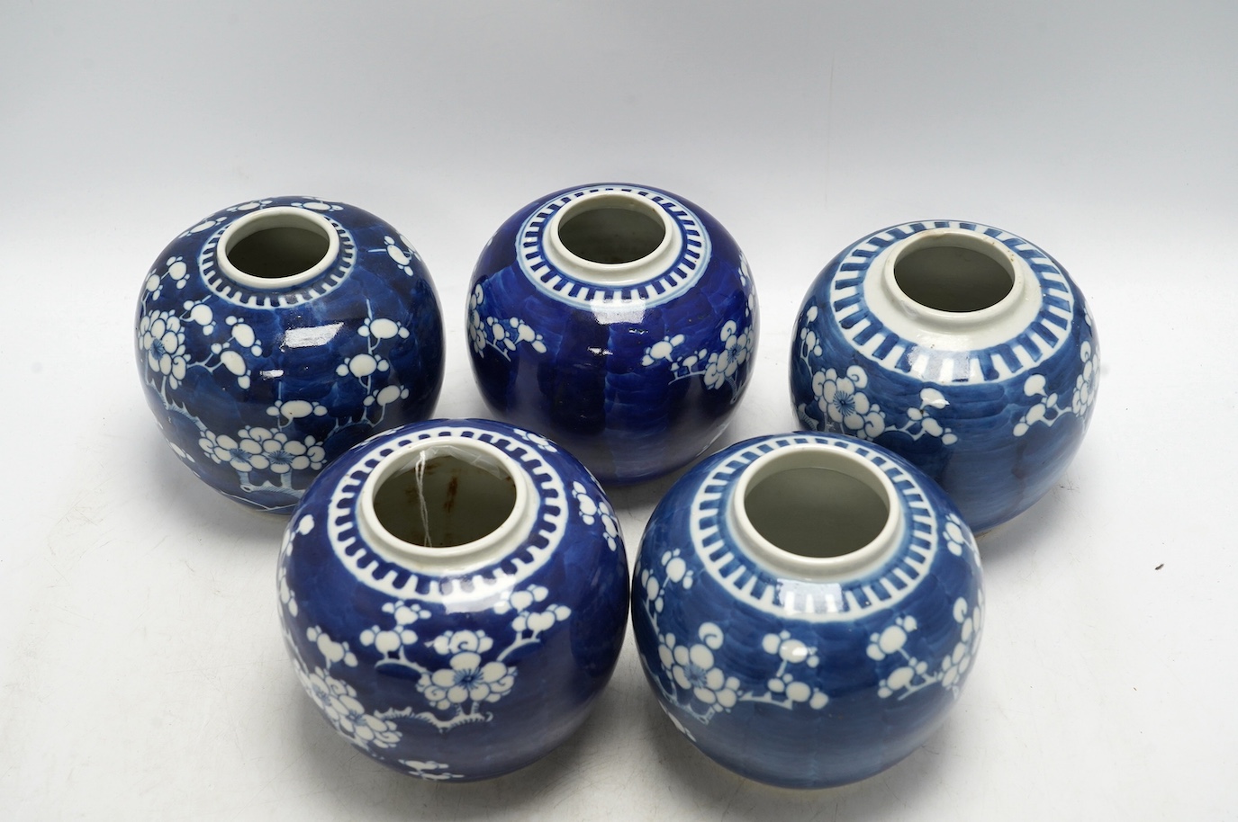 Five Chinese blue and white prunus jars, without covers, early 20th century, tallest 13cm high. Condition - one jar is chipped around the top, another has a large firing fault, the other two good